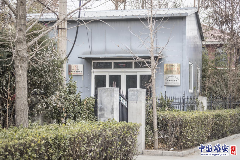 雄安新區(qū)雄縣，一間居民房在樹木的遮擋下顯得很不起眼。房子的門邊卻掛著“國家級非物質(zhì)文化遺產(chǎn)——鷹爪翻子拳”的金色招牌。李鑫 攝